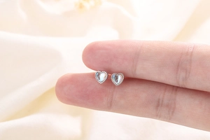 Macro shot of S925 sterling silver heart studs with luminous stones on fingertips