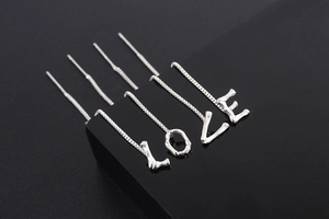 Detailed view of silver pull-through earrings spelling LOVE with bamboo texture finish