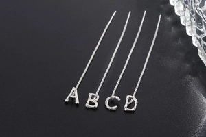 Detailed silver letter A B C D earrings with unique bamboo texture on dark surface