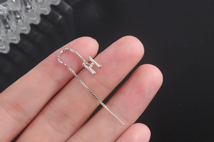 Macro shot of silver letter H ear wire with bamboo texture and minimalist box chain