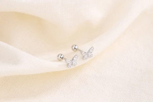 Detailed shot of silver butterfly screw back earrings with hollow carved wing patterns