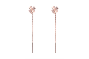 Macro detail of rose gold four-leaf clover pull-through earrings with zircon crystals