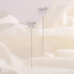 Boucles d'oreilles nœud papillon en argent S925 avec pampilles sur support blanc