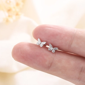 Silver butterfly screw back earrings with detailed 3D wing texture held by fingers