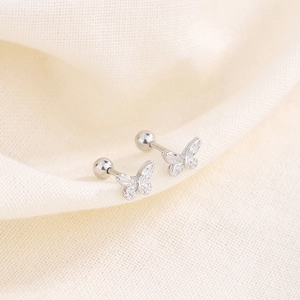 Polished silver butterfly screw back stud earrings on beige linen textured fabric