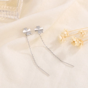 Elegant four-leaf clover drop earrings with cubic zirconia on a soft linen background