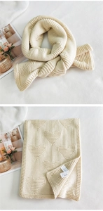 Detailed close-up of cream knit scarf featuring textured heart patterns and soft material