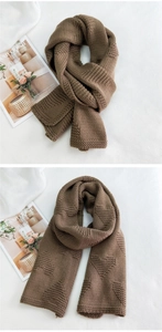 Detail of a brown knit scarf showing embossed heart patterns and thick wool texture