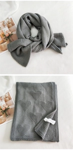 Detailed knit texture of a grey winter scarf featuring raised 3D heart patterns