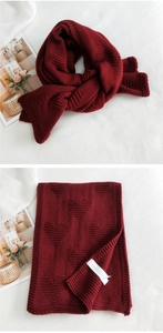 Close-up of thick burgundy knit scarf featuring heart embossed patterns and ribbed edges