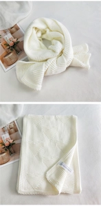 Detail of cream knit scarf showing textured heart patterns and soft thick yarn material