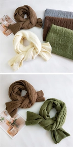 Detailed view of thick cable knit scarves in brown, cream, green and grey tones