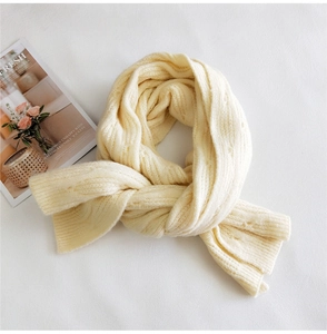 Close-up of thick ribbed knit texture on cream white winter scarf with a magazine