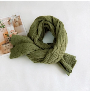 Close-up of thick grass green knitted scarf with cable and diamond stitch pattern