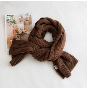 Close-up of thick cable knit texture on a long warm winter scarf in coffee brown