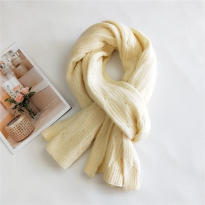 Chunky cream knit scarf with cable texture shown in a flat lay minimalist fashion style