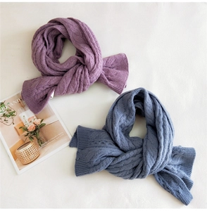 Detail of cross-knot knit scarves in violet and blue with thick cable patterns