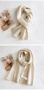 Detail of a thick cream cable-knit scarf showing intricate texture and soft winter material
