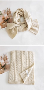 Detail of creamy knit scarf featuring thick cable knit texture and fabric wash label