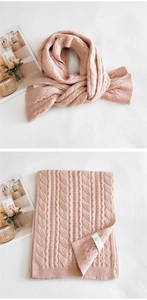 Detailed macro view of pink cable-knit scarf texture with brand tag and folded design