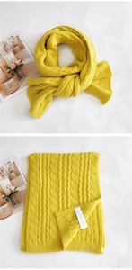 Detailed knit texture of yellow cable pattern scarf with ribbed edge and fabric label