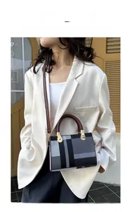 Detailed side view of plaid crossbody bag with woven handles and golden hardware