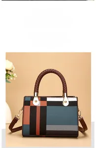 Detail of color-block geometric handbag with woven brown handle and gold metal hardware