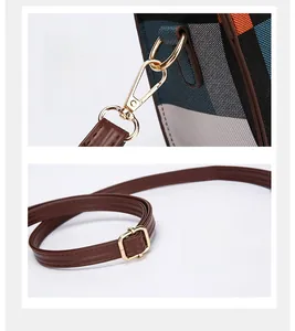 Detail of detachable metal hook and adjustable brown leather strap on plaid handbag