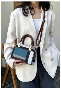Modern geometric shoulder bag shown on model with orange trim and woven handle details