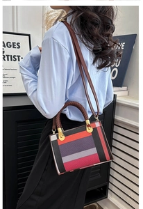 Detail of color-block geometric handbag featuring woven handles and leather shoulder strap