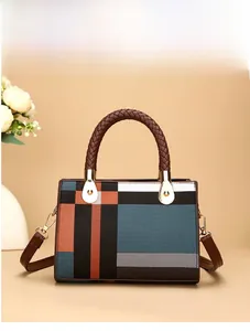 Detail of color-block tote bag with woven handles and detachable brown shoulder strap