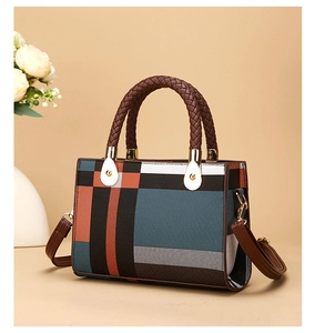 Detail of geometric patchwork shoulder bag with braided handle and gold hardware