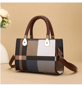 Detail of multi-color plaid handbag with woven leather handles and gold metal hardware