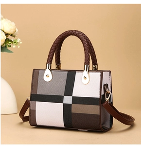 Detail of color-block tote bag with woven handles and floral decoration in warm studio light