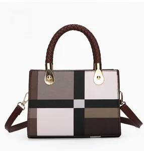 Detail of plaid patterned handbag featuring woven leather handles and gold metal hardware
