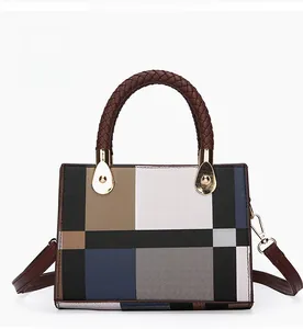 Detail of color-block tote bag with woven brown leather handles and gold metal hardware
