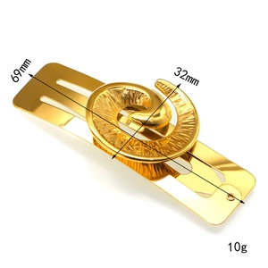 Detailed view of 18K gold rectangle hair clip with spiral motif and 69mm length dimensions