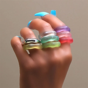Close-up of layered colorful wavy resin and metal rings on a model's hand