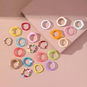 Flat lay of colorful resin rings with bead woven bands and butterfly charms