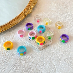 Colorful Y2K resin rings with geometric patterns displayed on white textured background