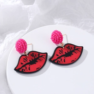 Exaggerated red lip drop earrings with fuchsia beads and acrylic finish on white tray