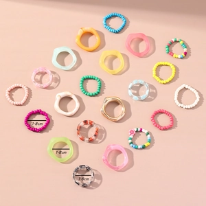 Détail de bagues papillon en résine colorée de 1,8 cm avec perles sur fond rose