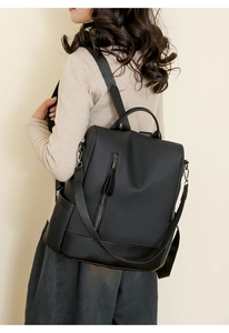 Detail of black soft PU leather backpack with vertical zip pocket and side pouches