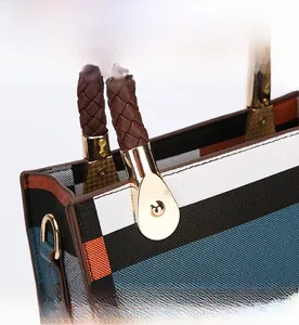 Close-up of woven leather handle and gold hardware on a geometric pattern tote bag