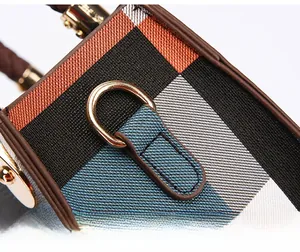 Detailed macro view of the textured plaid fabric and gold-toned metal hardware on the handbag