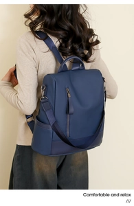 Detail view of the deep blue PU leather backpack showing side pockets and vertical zipper