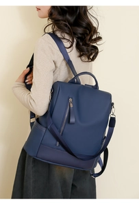 Side view of woman wearing deep blue soft PU leather backpack with sleek vertical zipper