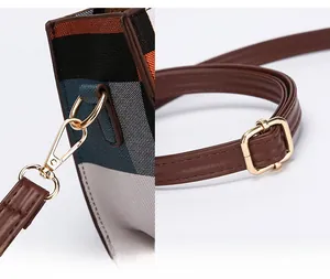 Detail of detachable shoulder strap with golden metal clasp on plaid handbag