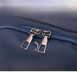 Detail of dual gunmetal zippers on dark blue lychee texture PU leather travel backpack
