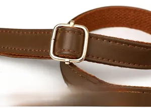 Detail eines dunkelbraunen Leder-Schultergurts mit verstellbarer goldener Metallschnalle